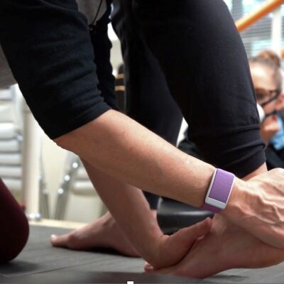 a photo of a physiotherapist working with a clients lower leg, ankle and foot on a body weight support treadmill